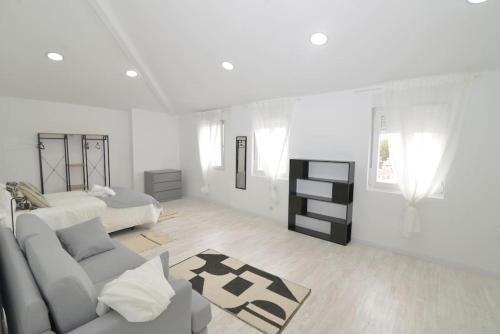 Cette chambre blanche dispose d'un canapé et d'un lit. dans l'établissement El apartamento de San Cisneros by Just-Room, à Santander