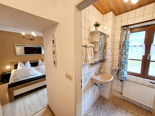 a bathroom with a bed and a sink in a room at Pension Etzerschlössl in Berchtesgaden