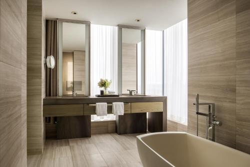 a bathroom with a tub and a sink and a mirror at Four Seasons Hotel Toronto in Toronto