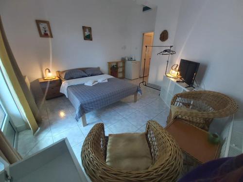 sypialnia z łóżkiem, krzesłami i telewizorem w obiekcie Apartmani Sladojević w mieście Mrkonjić Grad