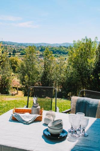 a white table with plates and wine glasses on it at Just Like Home - Quinta de Todos os Dias in Paredes de Coura