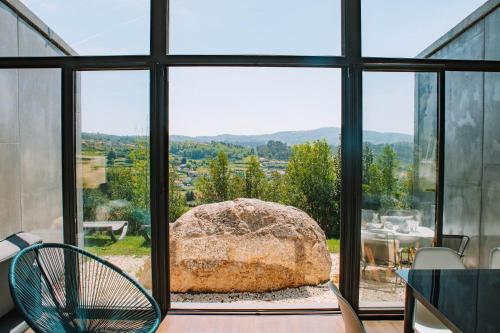 a room with a large window with a large rock at Just Like Home - Quinta de Todos os Dias in Paredes de Coura