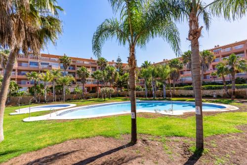 a pool with palm trees in front of a building at Brisas Almerimar R&R in El Ejido