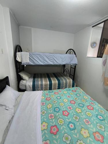 a small bedroom with two beds with a floral bedspread at Sumaq Wasi Caminos Del Inca in Lima