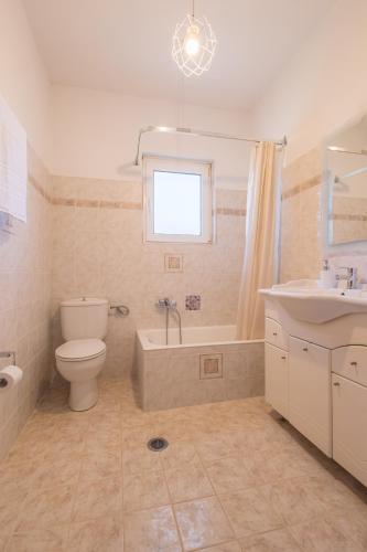 a bathroom with a toilet and a tub and a sink at Regina's House in Skopelos Town