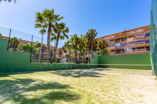 a tennis court with palm trees and a building at Brisas Almerimar R&R in El Ejido