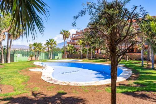 a swimming pool in a yard with palm trees at Brisas Almerimar R&R in El Ejido