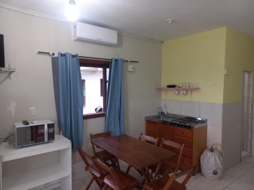eine kleine Küche mit einem Tisch und einer Mikrowelle in der Unterkunft Pousada Belas Praia da Riba in Imbituba