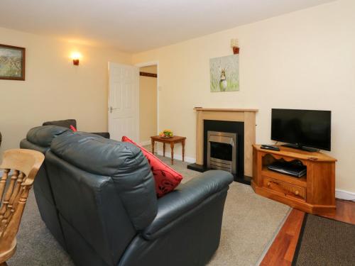 a living room with a leather couch and a flat screen tv at Newfield Apartment 1 in Broughton in Furness