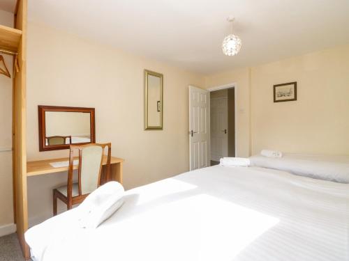 a bedroom with two beds and a desk and a mirror at Newfield Apartment 1 in Broughton in Furness