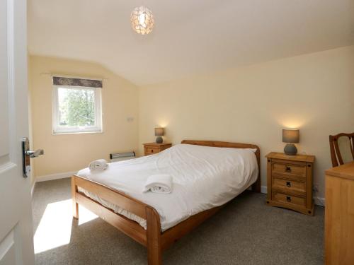 a bedroom with a bed and two night stands and a window at Newfield Apartment 1 in Broughton in Furness