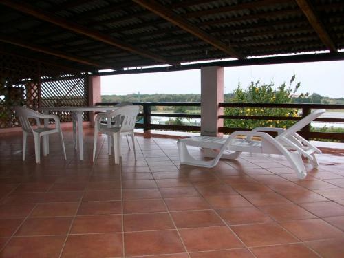 a patio with white chairs and a table on a roof at Bouganville Valledoria in Valledoria