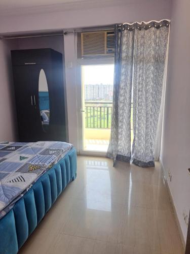 a bedroom with a bed and a large window at 2Bhk fully furnished flat. in Ghaziabad