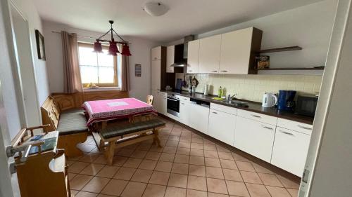 a kitchen with white cabinets and a table in it at Lisa's Ferienwohnung in Obing