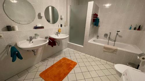 a bathroom with a sink and a tub and a mirror at Lisa's Ferienwohnung in Obing