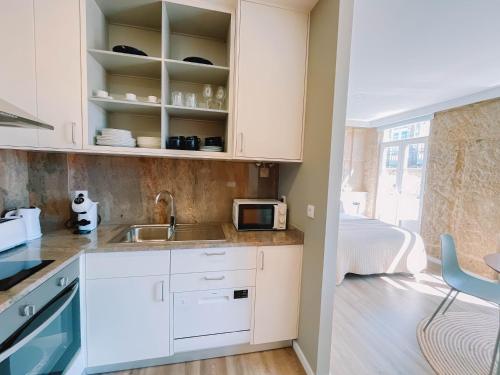 a kitchen with white cabinets and a sink at Just Like Home - Vilavelha Suites in Valença