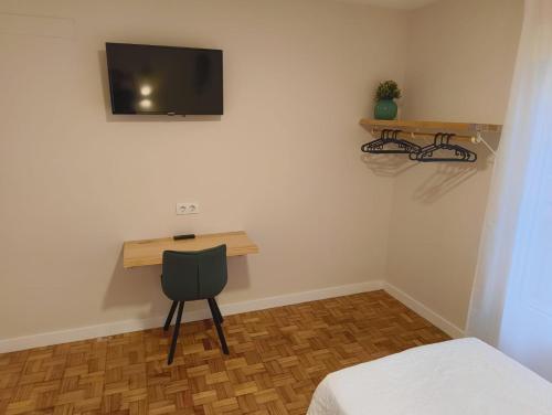 a room with a desk with a chair and a tv on the wall at Villa Galicia (Padrón) in Padrón