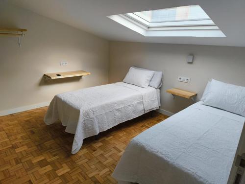 a bedroom with two beds and a skylight at Villa Galicia (Padrón) in Padrón