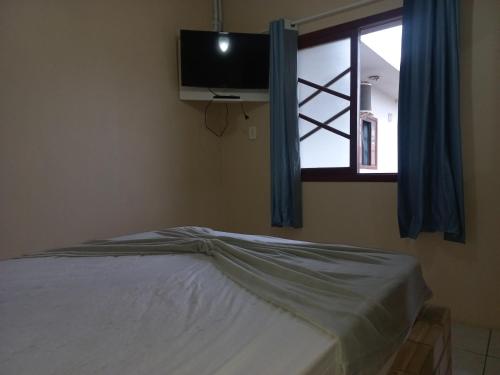 um quarto com uma cama, uma televisão e uma janela em Pousada Belas Praia quarto Praia dos amores em Imbituba