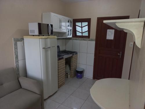 a small kitchen with a refrigerator and a microwave at Pousada Belas Praia quarto Praia dos amores in Imbituba