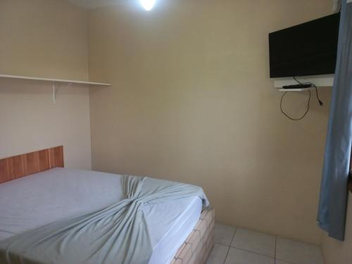 a bedroom with a bed and a flat screen tv at Pousada Belas Praia quarto Praia dos amores in Imbituba