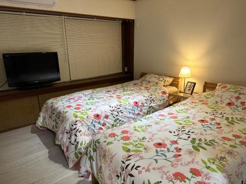 a bedroom with two beds and a flat screen tv at Guest House" Ro" takezaki in Amanogōchō