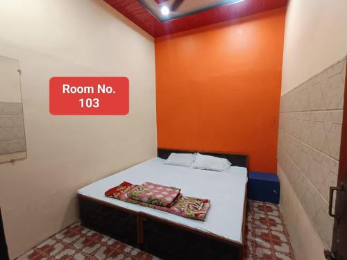 a small room with a bed with a room no sign at Agrawal guest house in Ujjain