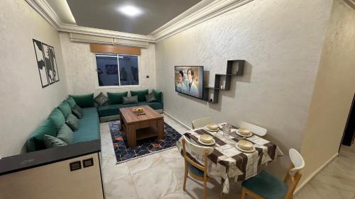 ein Wohnzimmer mit einem Tisch und einem grünen Sofa in der Unterkunft Lapatchi appart in Agadir