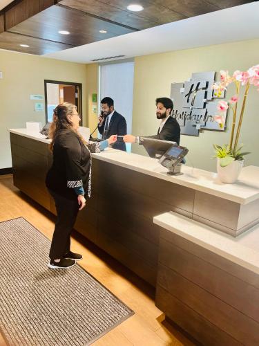 a woman standing in front of a counter in a store at Holiday Inn - Mississauga Toronto West by IHG in Mississauga