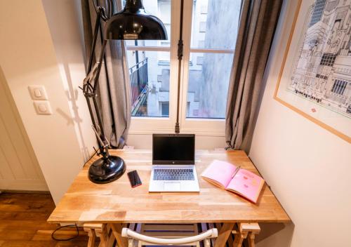 un ordinateur portable sur un bureau en bois avec une fenêtre dans l'établissement NEW / Le Robinson / Atypique /Centrale, à Nantes