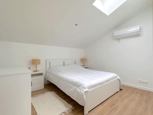 une chambre blanche avec un lit et un bureau dans l'établissement Maison à 5 min du Futuroscope, à Jaunay-Clan