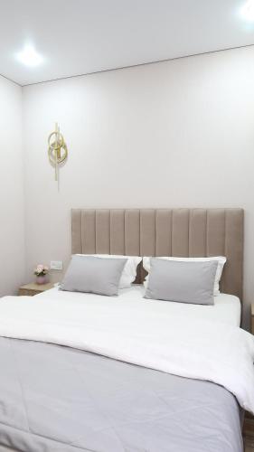 uma grande cama branca com lençóis e almofadas brancos em AG Hotel Nazarbaeva em Almaty