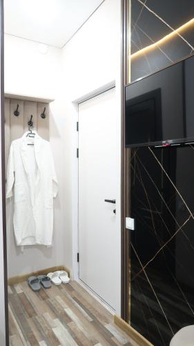 uma casa de banho com uma porta de correr, uma camisa branca e chinelos em AG Hotel Nazarbaeva em Almaty