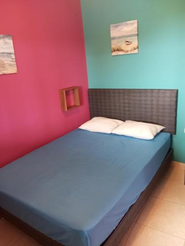 a bed in a room with pink and blue walls at Casita de Playa in Barranca
