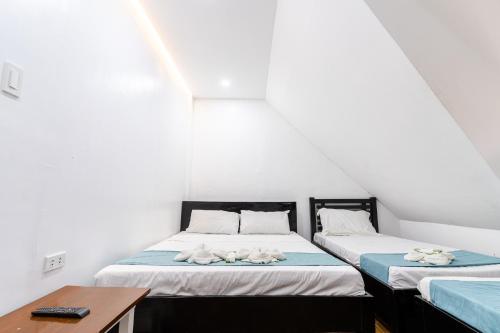 two twin beds in a room with a desk and a table at OCEANVIEW HOMESTAY in Alaminos