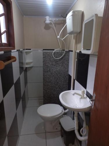 a bathroom with a white toilet and a sink at Pousada Belas Praia quarto Praia d'água in Imbituba
