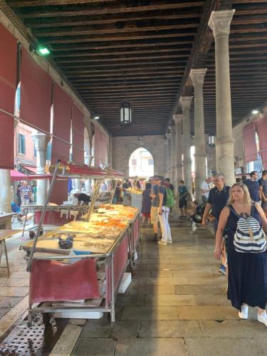 a group of people standing around a market with food at Rialto Mercato apartment suite in Venice