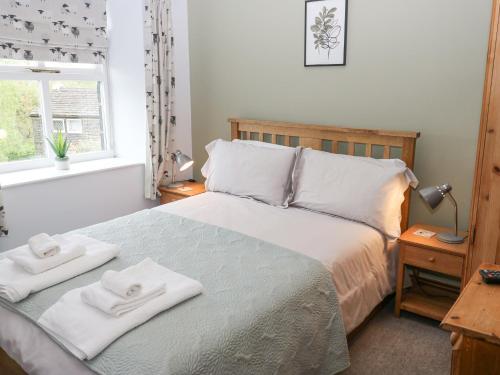 a bedroom with a bed with two towels on it at Bumble Cottage in Holmfirth