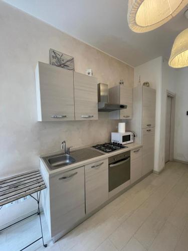 a kitchen with white cabinets and a sink at Casa Lorizia in Pietra Ligure