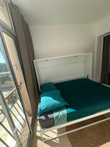 Cette chambre comprend un lit avec des oreillers verts et une fenêtre. dans l'établissement Un séjour idéal au Lavandou !, au Lavandou