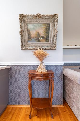 a painting on the wall above a table with a plant on it at Cozy apartments by the river near old town in Kaunas