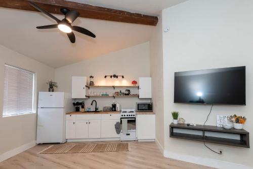 a kitchen with white cabinets and a flat screen tv at Cozy Studio Apt Close to the Gardens - King Bed in Huntsville