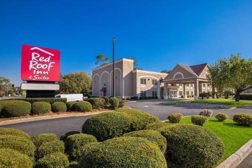 un hotel con un cartel de posada de techo rojo y arbustos en Red Roof Inn & Suites Albany, GA, en Albany