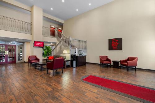 a lobby with red chairs and a red rug at Red Roof Inn & Suites Albany, GA in Albany