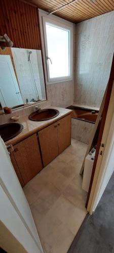 une petite cuisine avec deux lavabos et une fenêtre dans l'établissement Maison avec garage proche de la plage, à Les Sables-dʼOlonne