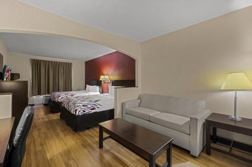 a hotel room with a bed and a couch at Red Roof Inn & Suites Albany, GA in Albany