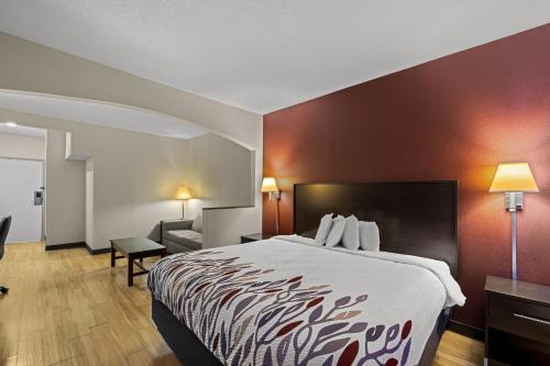 a hotel room with a large bed and a couch at Red Roof Inn & Suites Albany, GA in Albany