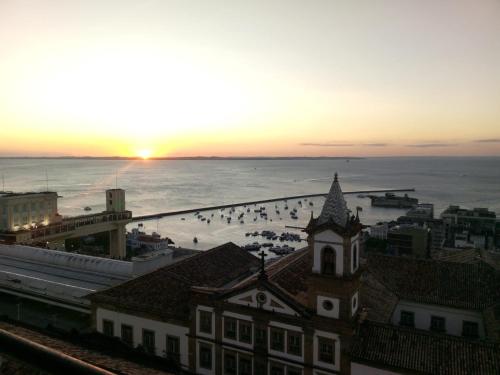 um pôr-do-sol sobre uma cidade com uma torre de relógio e o oceano em HOTEL Pon Pum Pelô em Salvador
