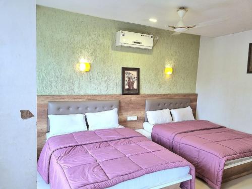 2 camas en una habitación con sábanas moradas en City pride family en Mahabaleshwar