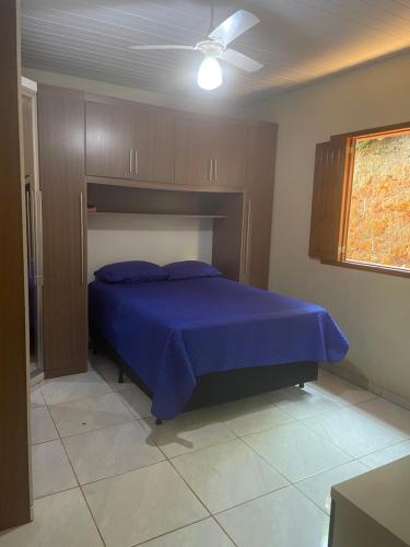 Schlafzimmer mit einem blauen Bett und einem Deckenventilator in der Unterkunft Casa de campo in Presidente Soares